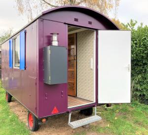 a purple tiny house on wheels with a door open at Pipowagen Paarse Opal in Lienden