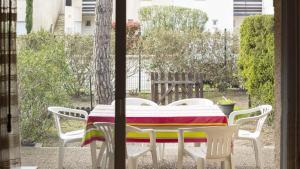 - une table avec des chaises blanches et une couverture colorée dans l'établissement Eleuthera- 174- Appart en rez de jardin- 4pers, au Cap d'Agde