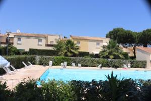 a swimming pool with chairs and trees and buildings at Eleuthera- 174- Appart en rez de jardin- 4pers in Cap d'Agde