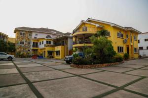 a parking lot with yellow buildings and cars at Midindi Hotel in Accra