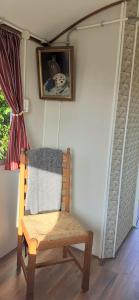 una silla de madera en una habitación con una foto en la pared en Pipowagen Paarse Opal, en Lienden
