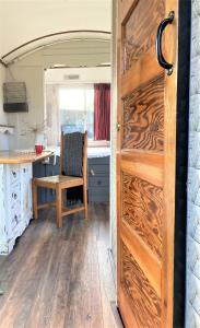 a door in a kitchen with a table and a chair at Pipowagen Paarse Opal in Lienden