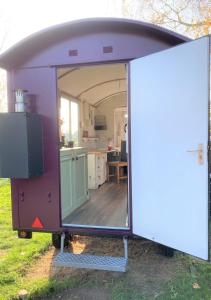 remolque púrpura con puerta y cocina en Pipowagen Paarse Opal, en Lienden