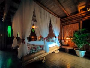 a bedroom with a canopy bed with curtains at Cabaña Manantial del Turpial in Jardin