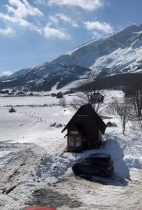 un'auto parcheggiata nella neve accanto a una cabina di Koliba Činčila a Žabljak