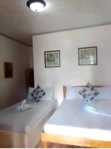 two twin beds in a room with two pictures on the wall at Domos Native Guest House in Panglao