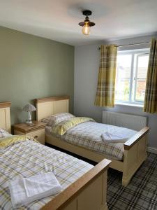 a bedroom with two beds and a window at Holly Tree Cottage in Barmby on the Moor