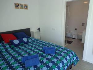a bedroom with a bed with blue and red pillows at Villa met het rustige strand van Salgado op wandelafstand in São Martinho do Porto