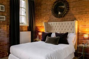 a bedroom with a white bed with a brick wall at Betts (Private Ensuite room) at Bicester Heritage in Bicester