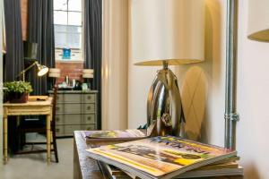 een tafel met een lamp en een tijdschrift erop bij Betts (Private Ensuite room) at Bicester Heritage in Bicester