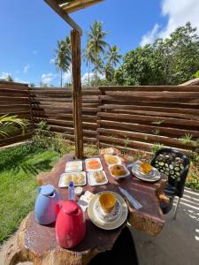 a picnic table with food and tea pots on it at Suítes Naldiane in Imbassai