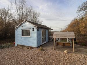 una pequeña casa azul con un banco en un patio en Art Studio en Blandford Forum
