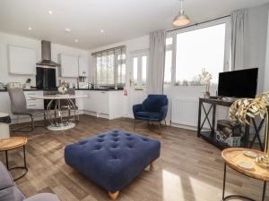 a living room with a blue ottoman and a kitchen at Dreamwood in Blandford Forum