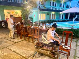 Ein Mann, der Essen auf einem Grill vor einem Restaurant kocht in der Unterkunft Phu Long Resort & Bar Phu Quoc in Phu Quoc