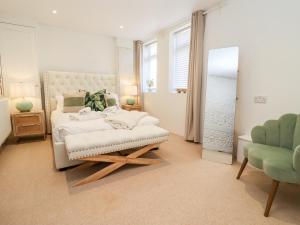a white bedroom with a bed and a chair at Primrose in Blandford Forum