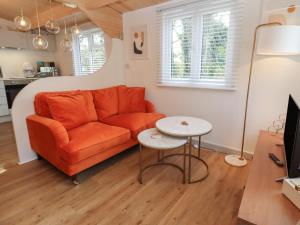 a living room with an orange couch and a table at Copper Beach in Blandford Forum