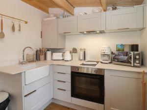 a kitchen with white cabinets and a stove top oven at Copper Beach in Blandford Forum