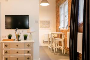 a living room with a television and a dresser with a table at Rotheram (Suite) at Bicester Heritage in Bicester