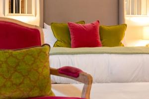 Un dormitorio con una cama con almohadas de colores y una silla. en Rotheram (Suite) at Bicester Heritage en Bicester