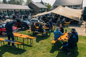 a group of people sitting at picnic tables at a car show at Rotheram (Suite) at Bicester Heritage in Bicester
