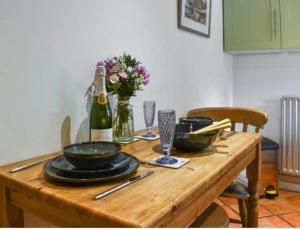 a wooden table with plates and glasses and a bottle of wine at The Hideaway in Shepton Mallet