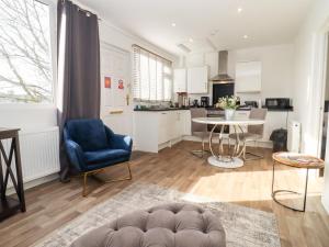 a kitchen and living room with a blue chair and a table at Stillness in Blandford Forum