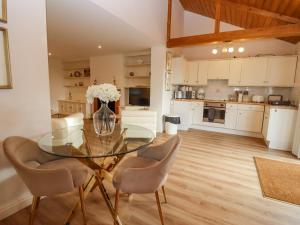 a kitchen and dining room with a glass table and chairs at Snowdrop in Blandford Forum