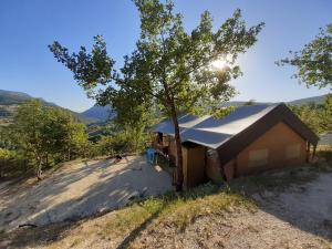 a house with a tree next to a dirt road at Camping Villaggio Il Collaccio in Preci