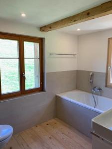uma casa de banho com uma banheira, um lavatório e um WC. em Haus Stelz em Nesslau