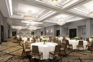 un salón de banquetes con mesas y sillas blancas y lámparas de araña en Philadelphia Marriott Old City, en Filadelfia