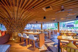 un restaurante con techos de madera, mesas y sillas en Courtyard by Marriott Bali Nusa Dua Resort en Nusa Dua