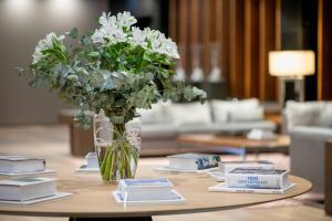 eine Vase mit Blumen auf einem Tisch mit Büchern in der Unterkunft AC Hotel Oviedo Fórum by Marriott in Oviedo