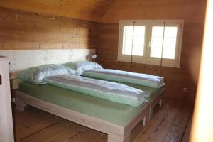 two beds in a wooden room with two windows at Ferienhaus, Stöckli Klingenbuch 20 in Rehetobel