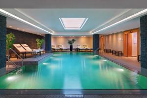 a swimming pool in a hotel lobby with chairs and tables at Le Méridien Hamburg in Hamburg