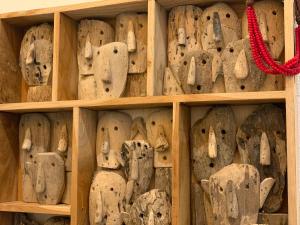 un estante lleno de máscaras de madera en Le Pavillon de Flore by Maison Brasseurs d'Etoiles en Lieja
