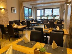 un restaurant avec des tables et des chaises en bois ainsi que des fenêtres dans l'établissement Hotel Sonne, à Stupferich