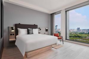 a bedroom with a white bed and a large window at Moxy Taichung in Taichung