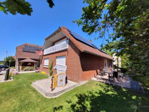 ein Backsteinhaus mit Rasen davor in der Unterkunft Naturwert Hotel Garni Ursula in Krummhörn