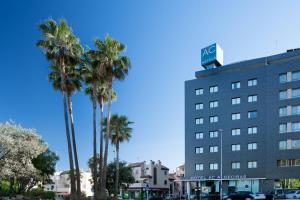 a hotel with palm trees in front of a building at AC Hotel Algeciras by Marriott in Algeciras