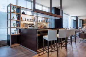 a bar in a restaurant with white bar stools at AC Hotel Algeciras by Marriott in Algeciras