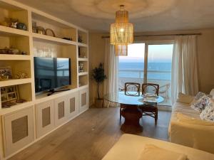 Sala de estar con mesa y vistas al océano en Maravilloso apartamento en primera línea de playa., en Torreguadiaro
