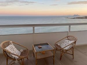 duas cadeiras e uma mesa numa varanda com o oceano em Maravilloso apartamento en primera línea de playa. em Torreguadiaro