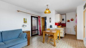un salon avec un canapé bleu et une table ainsi qu'une cuisine dans l'établissement Port Lano- 172- Appart bonne exposition- 4 pers, au Cap d'Agde
