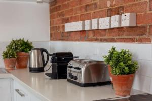 a kitchen counter with a toaster and potted plants on it at Bowen-Buscarlet (Large Suite) at Bicester Heritage in Bicester