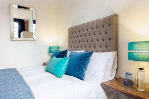 um quarto com uma cama grande e almofadas azuis em Bowen-Buscarlet (Large Suite) at Bicester Heritage em Bicester