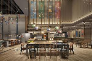 Four Points by Sheraton Tianjin National Convention and Exhibition Center في تيانجين: غرفة طعام مع طاولات وكراسي ونوافذ زجاجية ملطخة