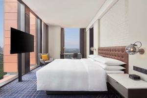 a hotel room with a bed and a flat screen tv at Four Points by Sheraton Tianjin National Convention and Exhibition Center in Tianjin