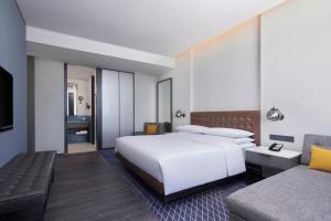 a bedroom with a large white bed and a couch at Four Points by Sheraton Tianjin National Convention and Exhibition Center in Tianjin
