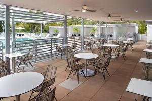 マイアミにあるコー​​トヤード マイアミ ココナッツ グローブのテーブルと椅子のあるレストラン、プールを提供しています。