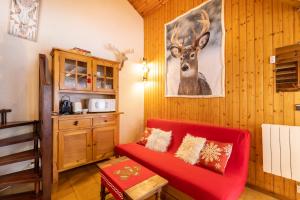 ボルケール・ピレネー 2000にあるChalet les Lupins Bleus au pied des pistes Font-Romeu Pyrénées 2000の赤いソファと鹿の絵が飾られたリビングルーム